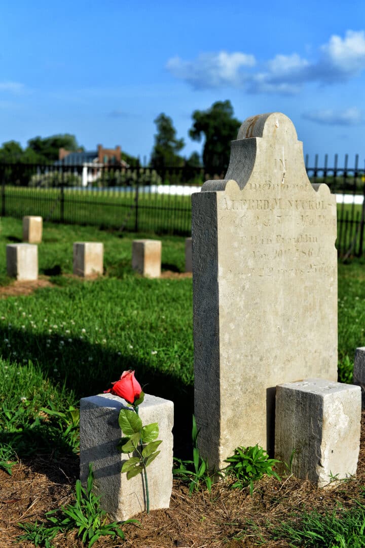 Cemetery marker with rose and Carnton in background.