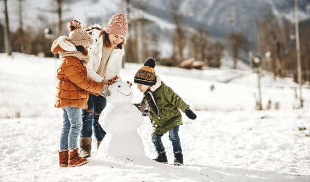 Family enjoying a winter break activity in Franklin, Tennessee, building a snowman together.
