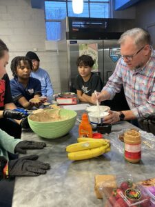 AMH's Stephen Kerr works with Columbia students in the kitchen to create the S'mores Tres Leches.