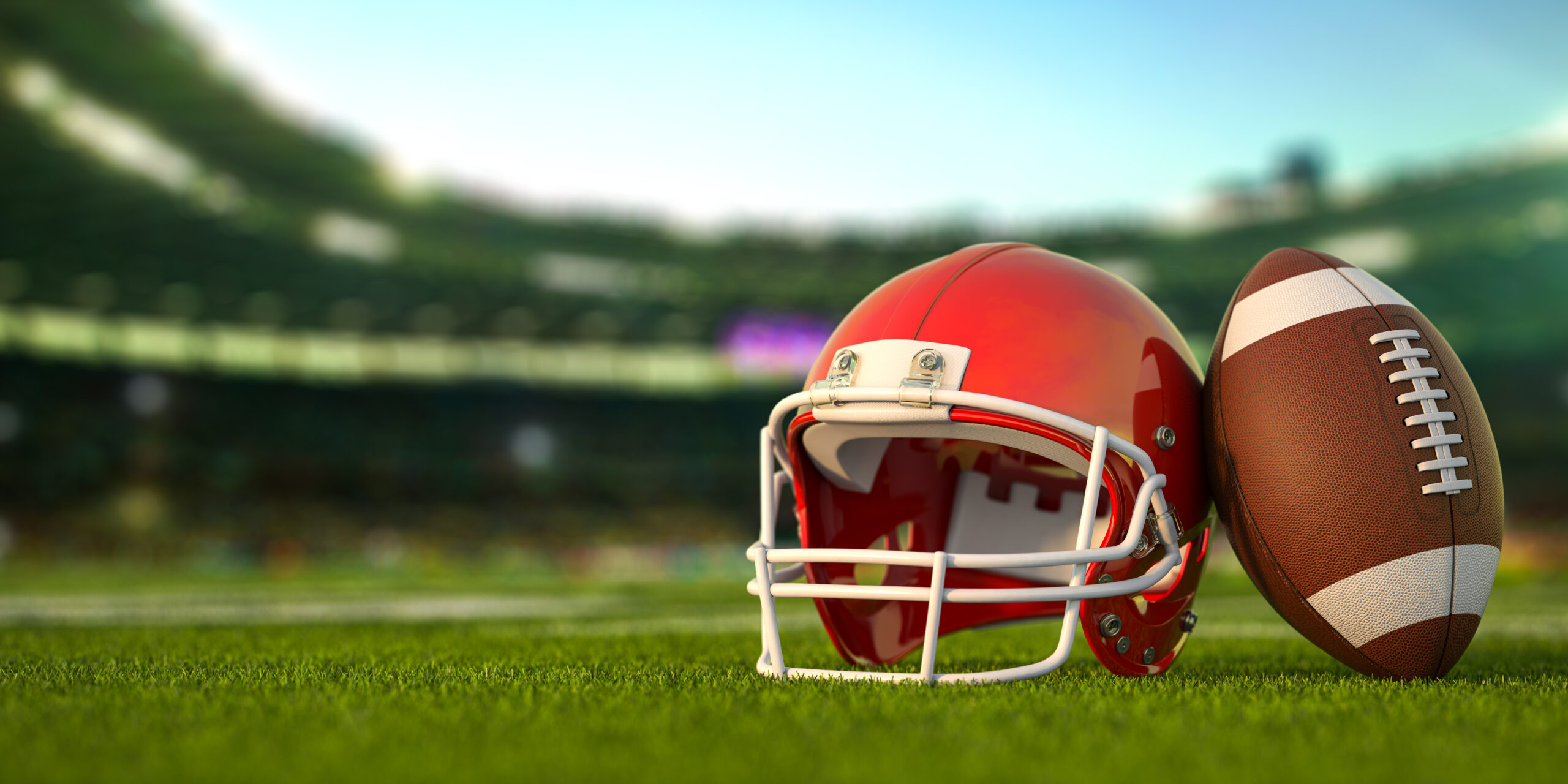 American football ball and helmet on the grass of football arena