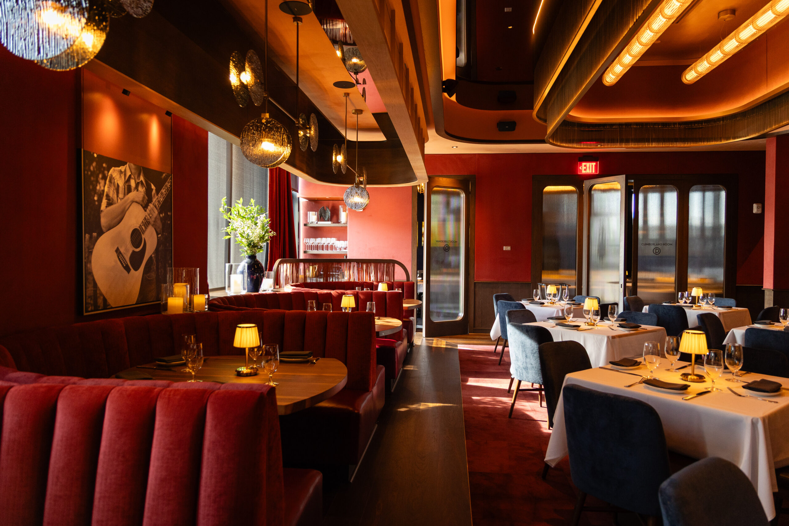 Ocean Prime Nashville private dining room with red booths, white tablecloths, and warm lighting at Nashville Yards