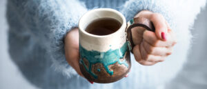 Girl holding cup of coffee in her hands.