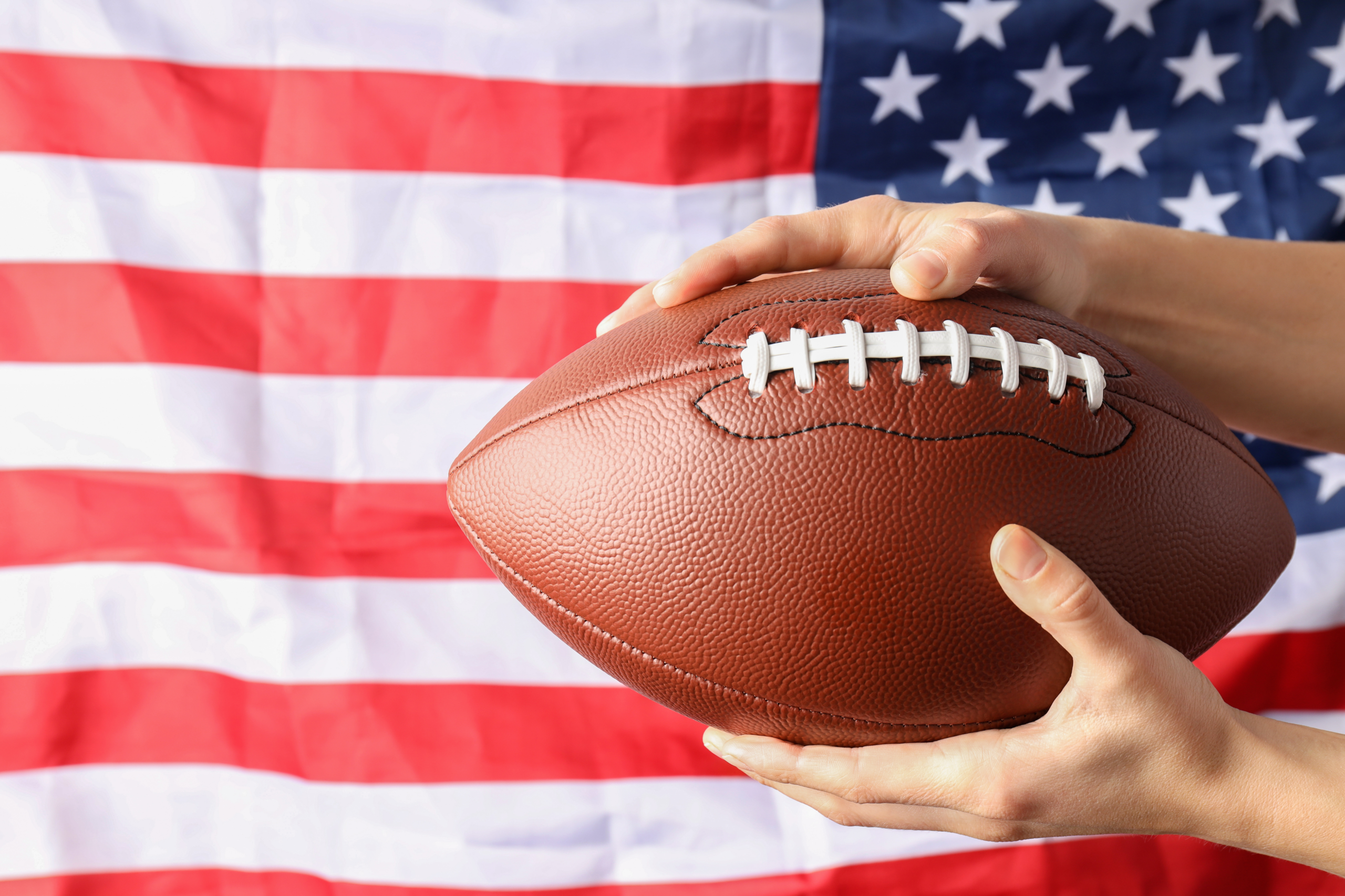 Super Bowl watch parties in Franklin and Nashville, TN, list of sports bars, restaurants and family entertainment centers showing the big football game_Football in hands with the US flag as background.