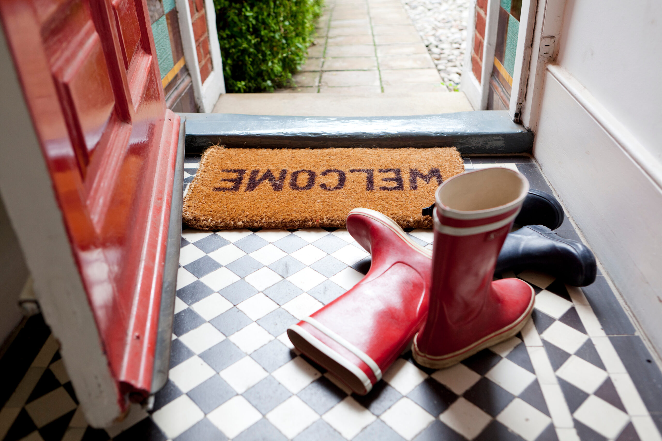 Welcome mat, open front door, red rain boots in a Franklin, TN home.