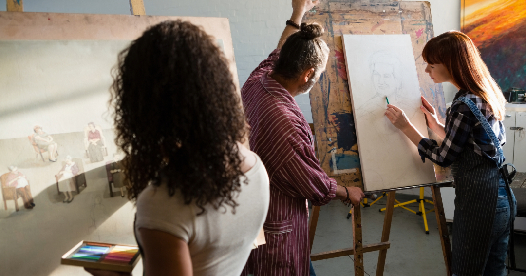 Adult and teen art classes in Franklin, 3 people in an art class, faced away from the camera and toward their canvases. 