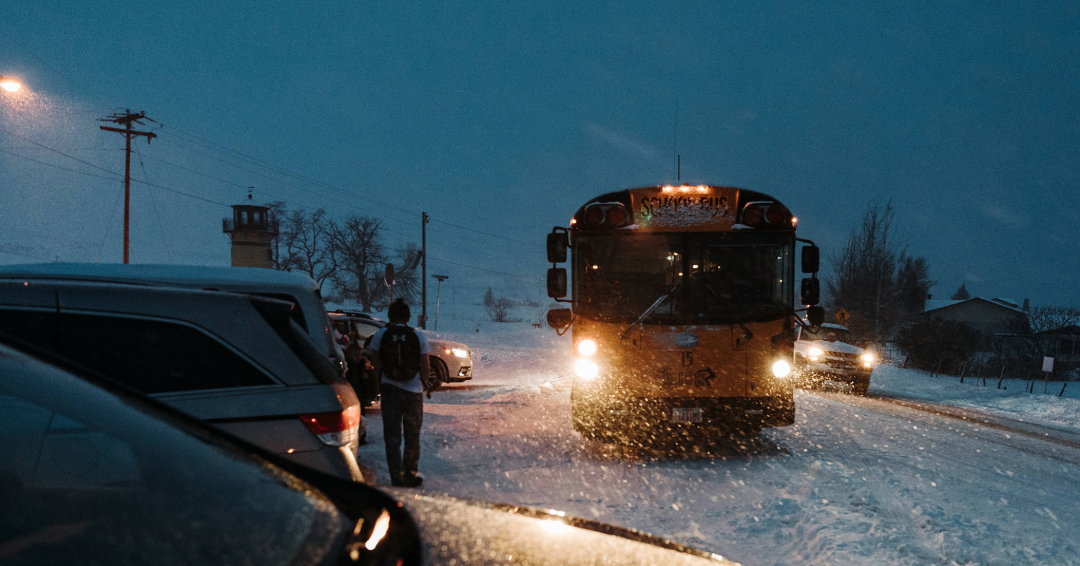 A bus in the snow at night, driving through a parking lot, Williamson County, TN winter safety tips.