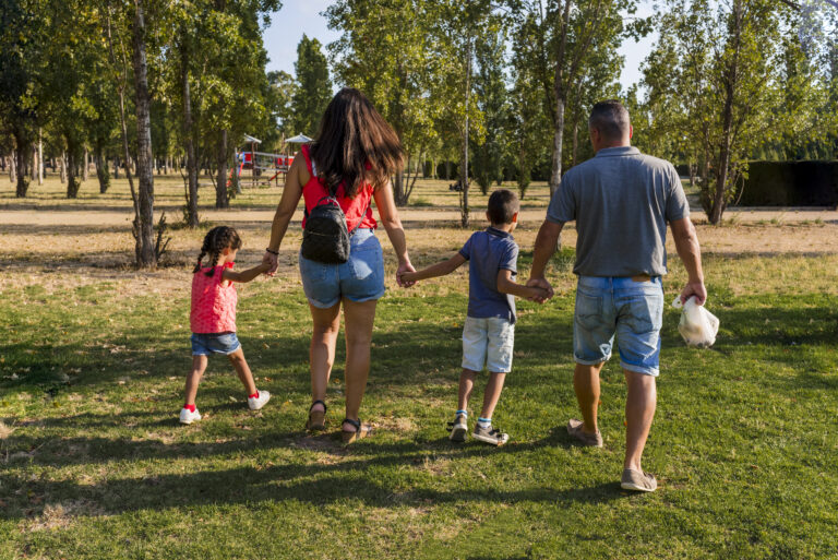 A family of four walking through a park.