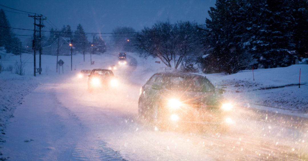 Several cars driving on a snow covered road at night, Williamson County, TN winter safety tips.