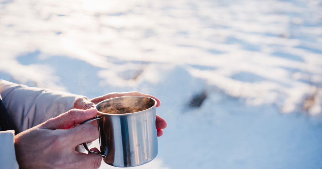 Hands holding a mug outdoors with snow, Williamson County, TN winter safety tips from FranklinIs.