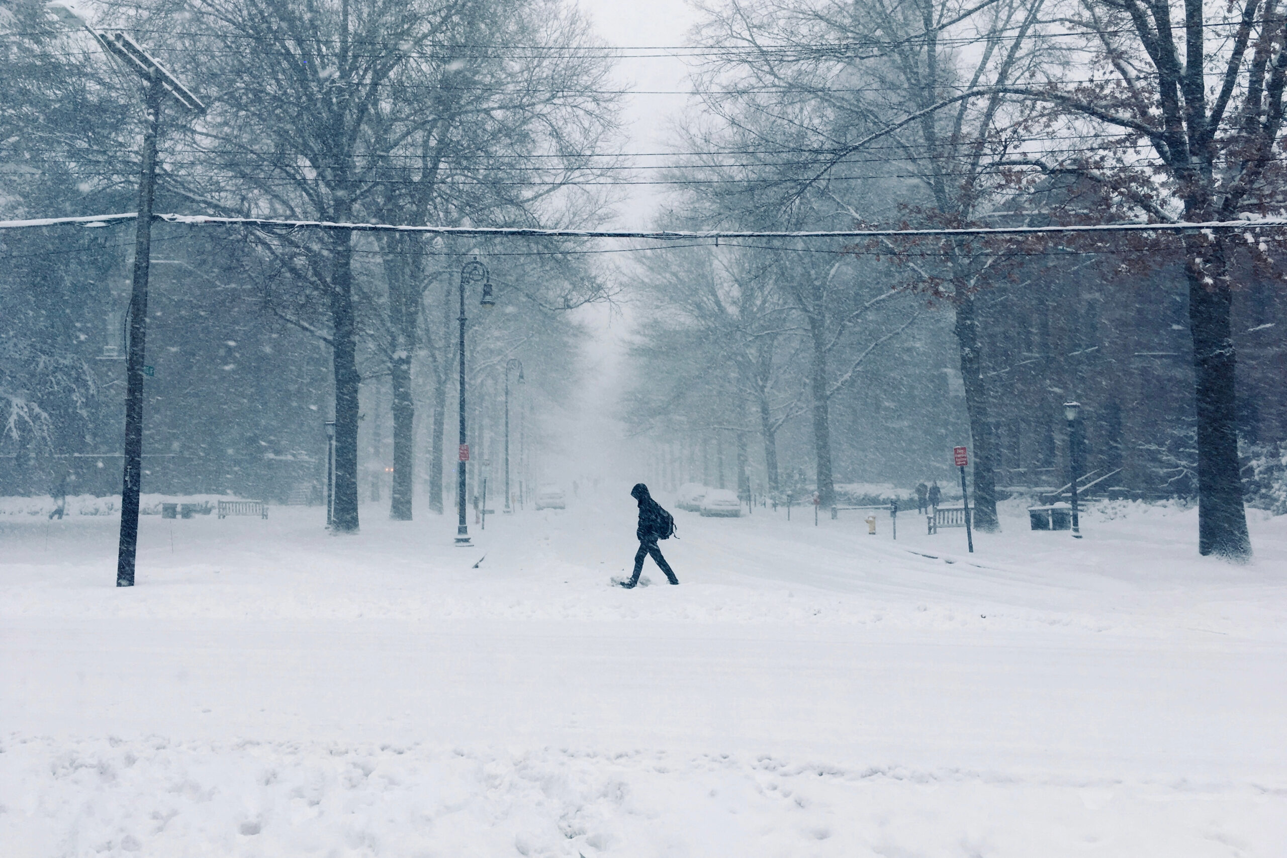 A person is walking on a snowy, gray street.