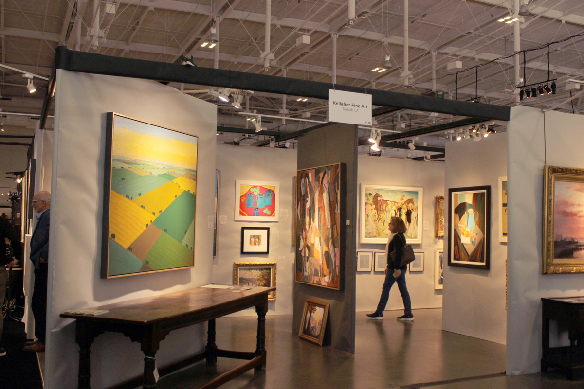 A woman is walking through a painting gallery at the Antiques & Garden Show in Nashville, TN.