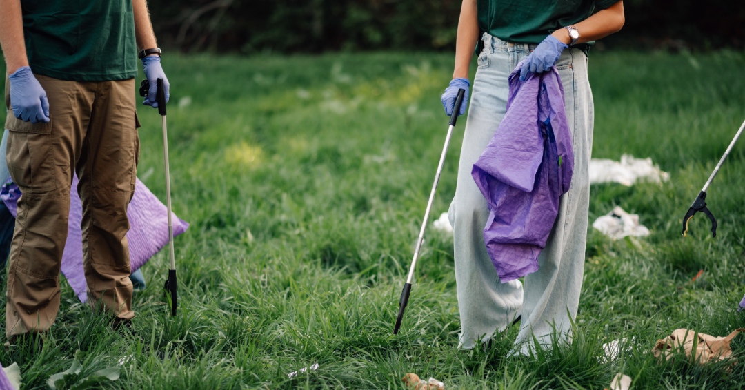 Two people pick up trash in a field, volunteering in Franklin, Tennessee.