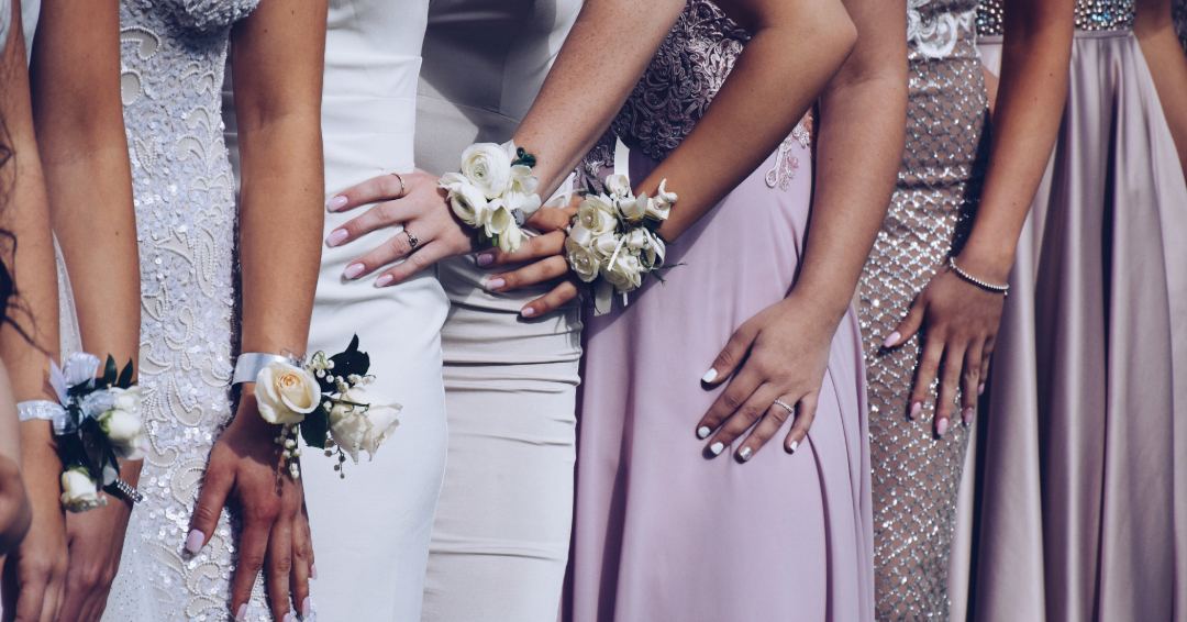 A line of girls in their prom dresses, with corsages on.