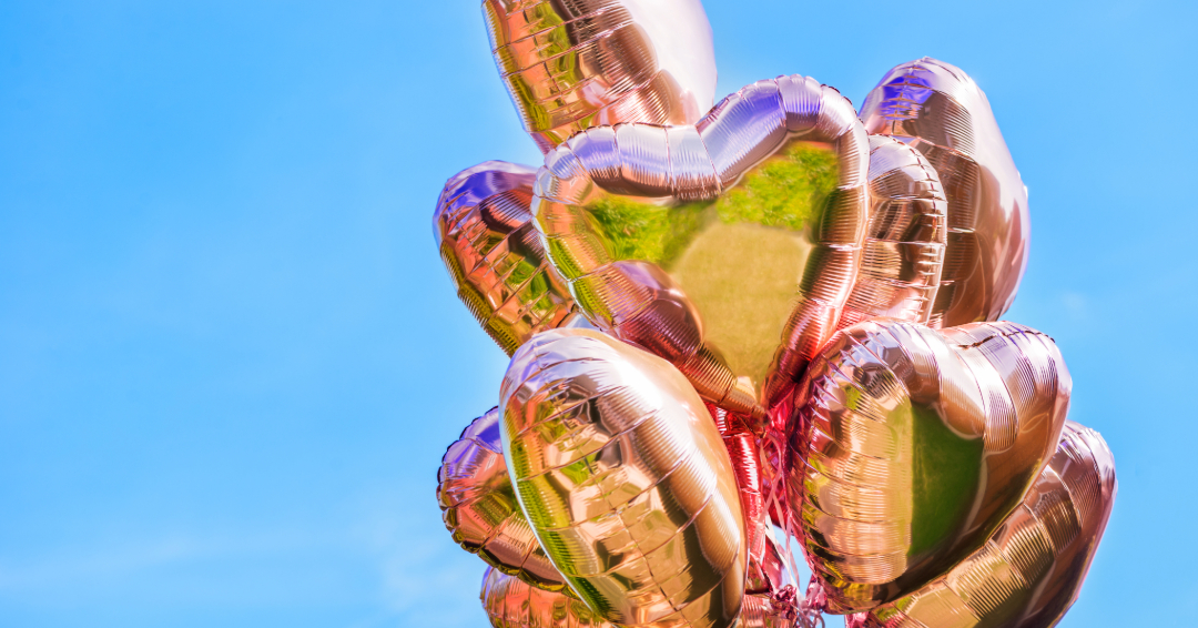 A bunch of metallic, pink heart balloons.