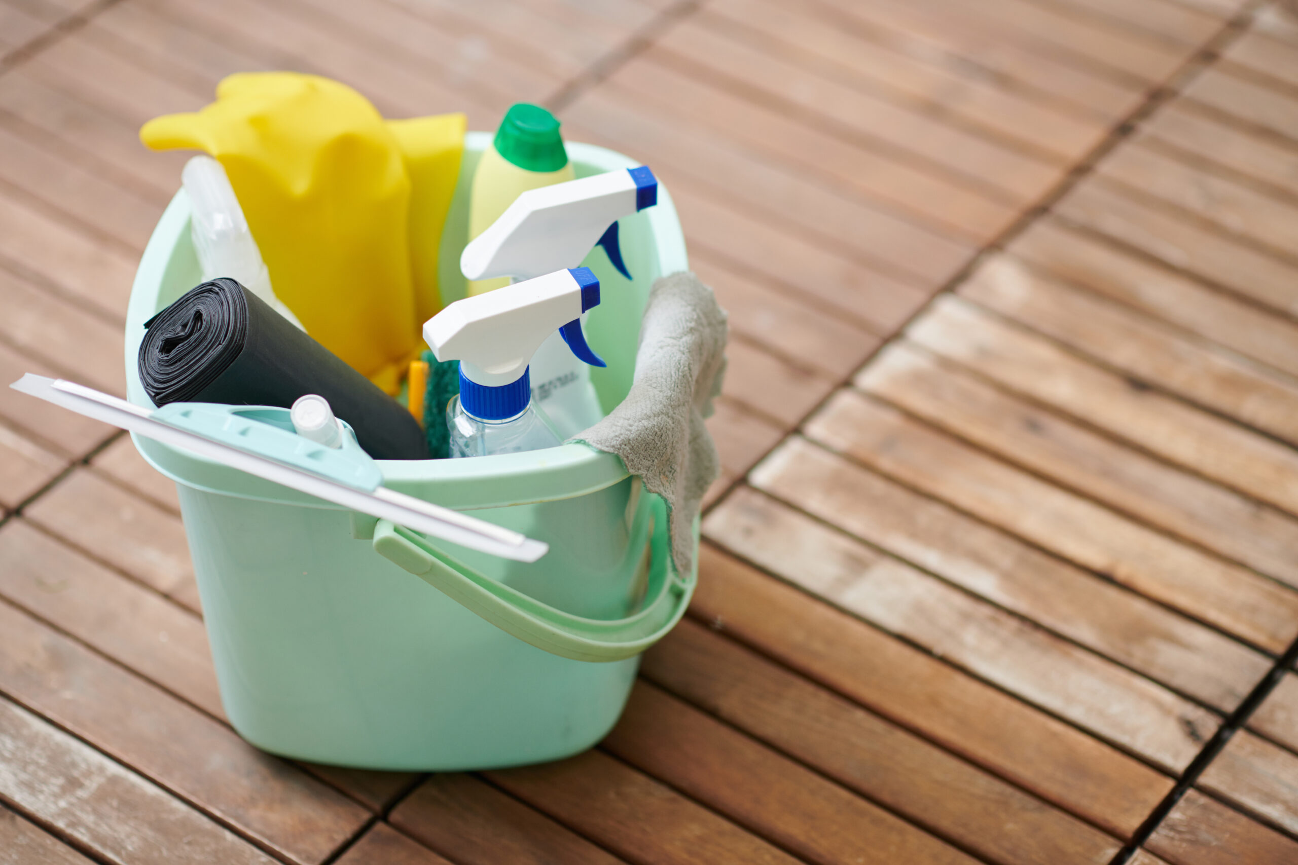 A mint green bucket is full of cleaning supplies.