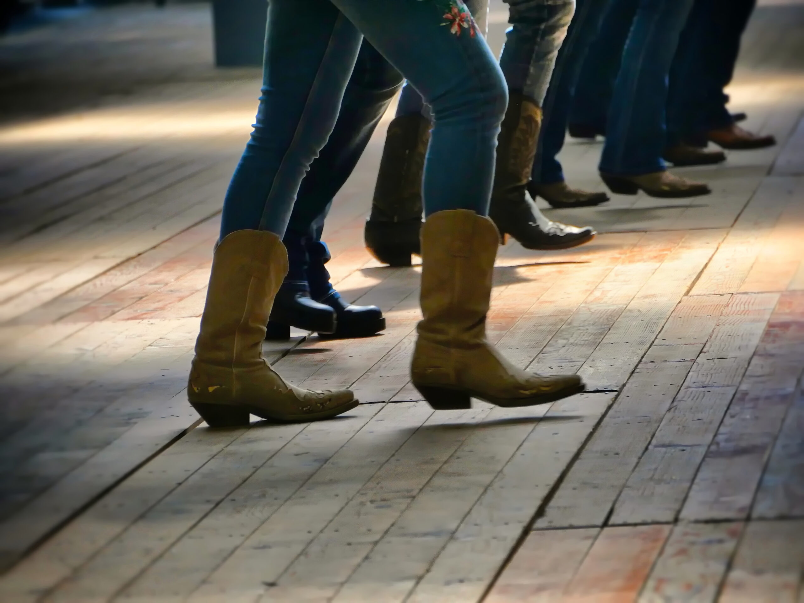 People performing a line dance, wearing cowboy boots.