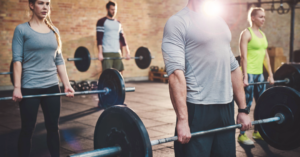 A group fitness class participates in a workout that includes deadlifting.