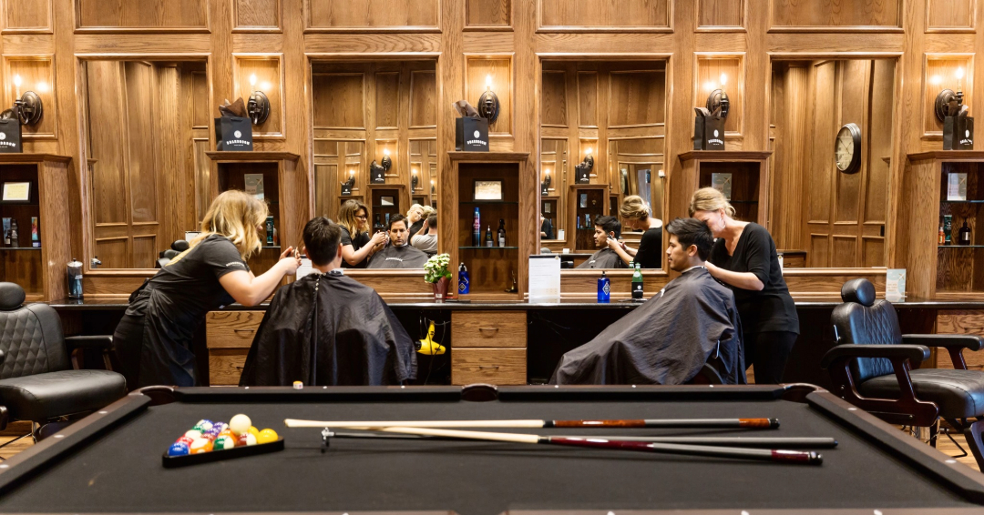 Grooming services in Franklin and Brentwood, TN, featuring Boardroom Styling Lounge, with clients in a wood-paneled barbershop with a pool table.