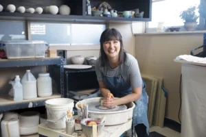 Potter, Melodie Grace of Common Grace Pottery studio in Nashville, TN, working on ceramics wheel at her home studio.