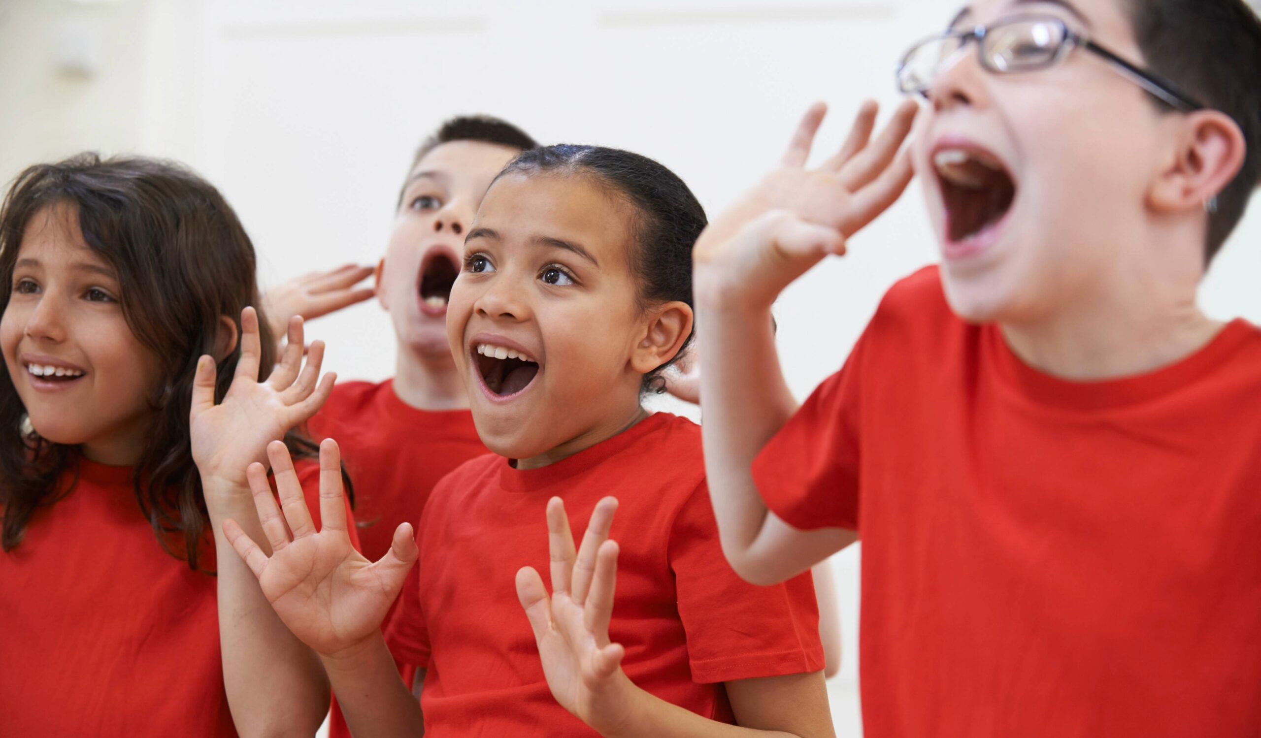 Performance-based learning for kids in Franklin, TN, four children in red shirts in drama class.