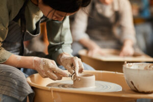 An artisan in a Franklin pottery workshop works with a piece of clay on a pottery wheel.
