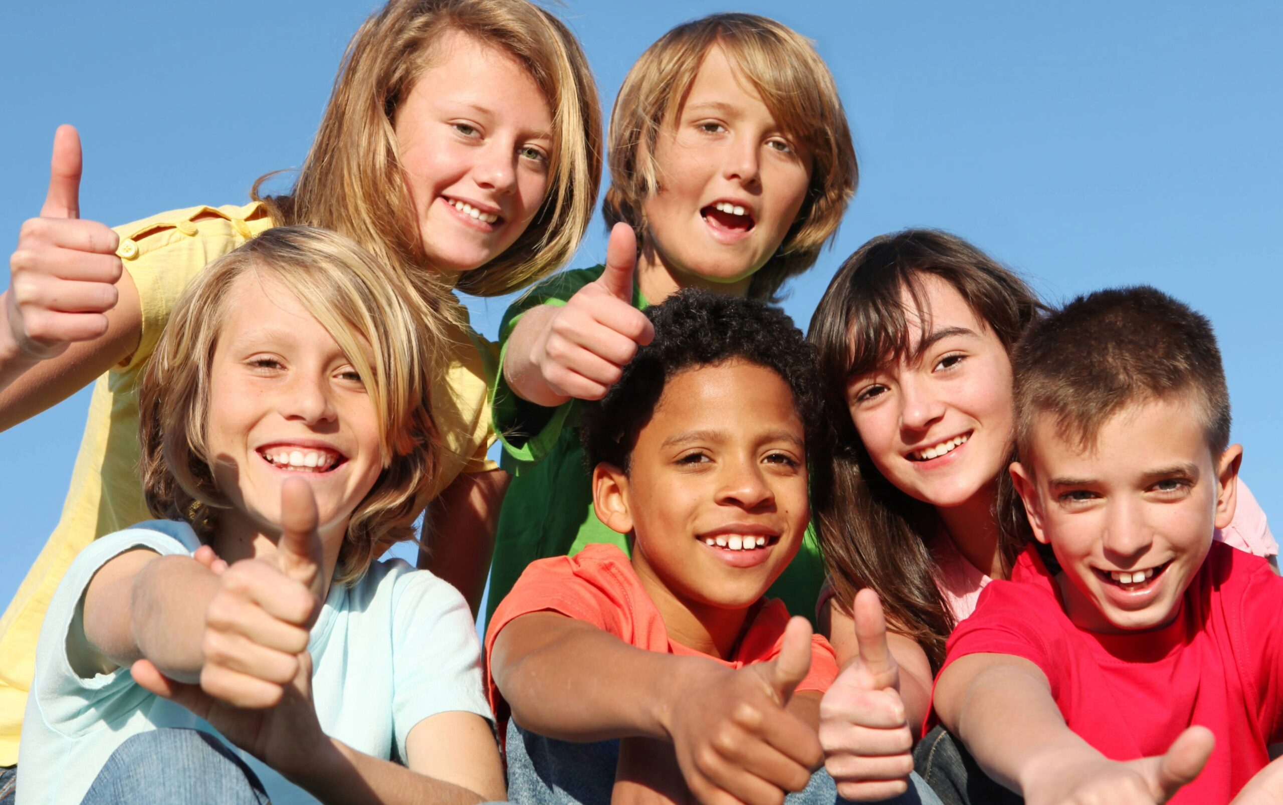 Supporting children across Williamson County, TN, shown by a diverse group of smiling kids giving thumbs up outdoors, representing community support, youth services, and positive development.