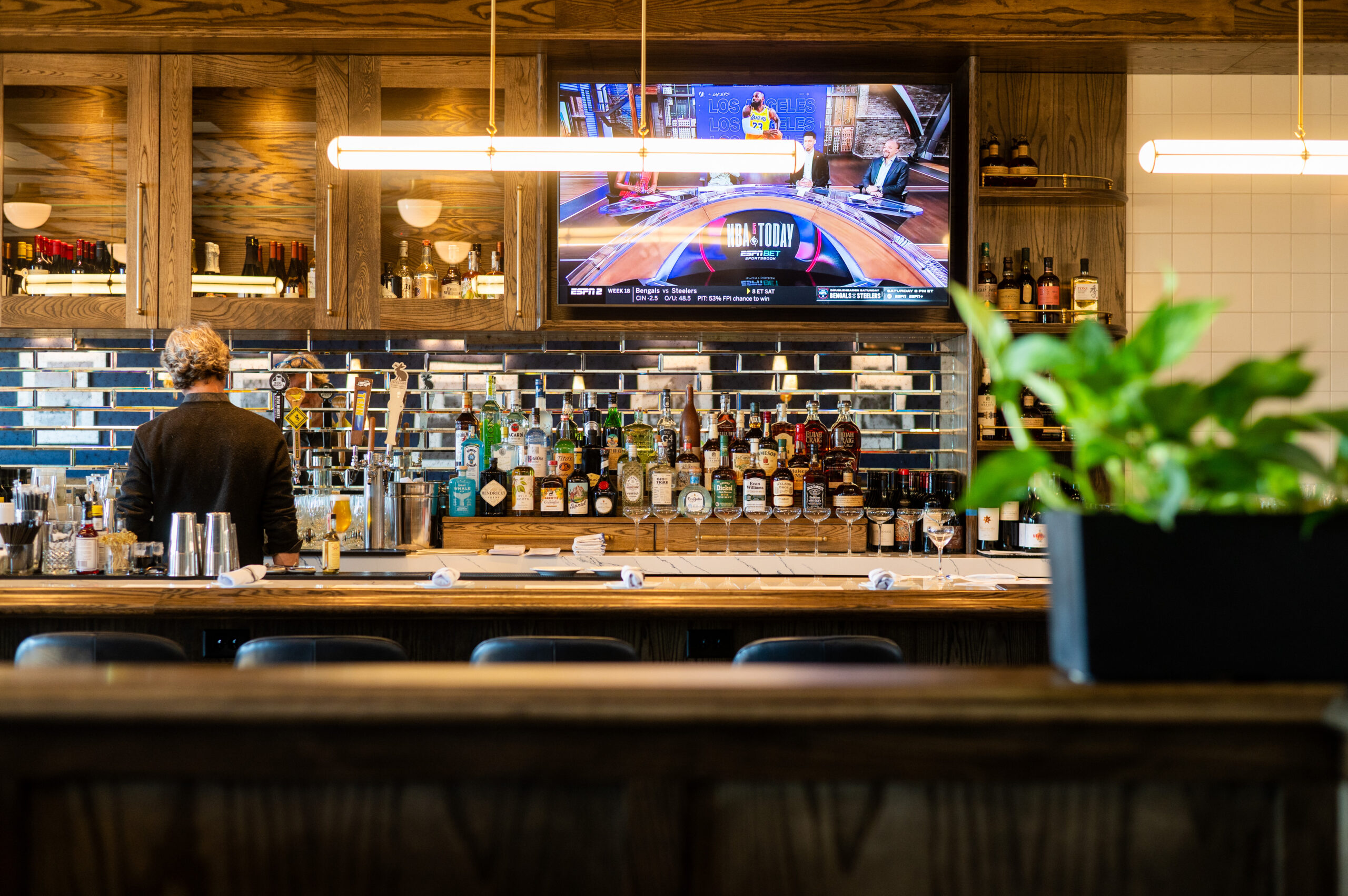 Bar area at Karrington Rowe in Brentwood, TN with bartender, liquor shelves, and television above the bar._Kenzie Leigh Photography