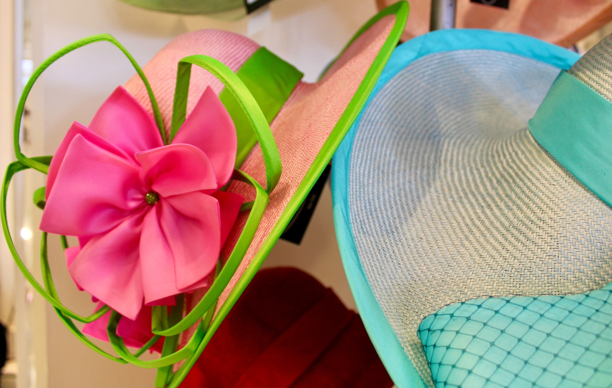 Bright pink and blue hats with decorative accents by Christine Moore displayed for Iroquois Steeplechase fashion in Nashville