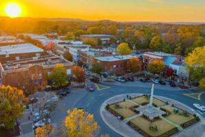 Aerial of Downtown Franklin TN at sunset with Public Square roundabout, monument, brick buildings and fall trees.