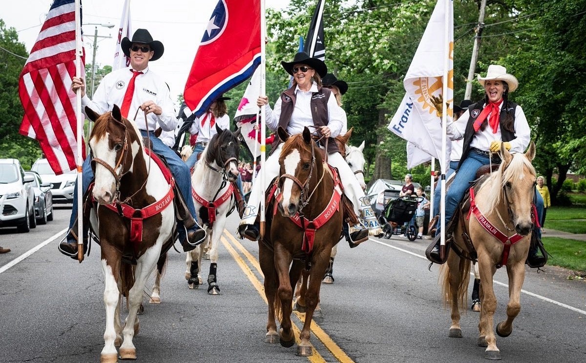 Franklin Rodeo riders on horseback carrying flags during the Franklin Rodeo Parade in downtown Franklin, Tennessee