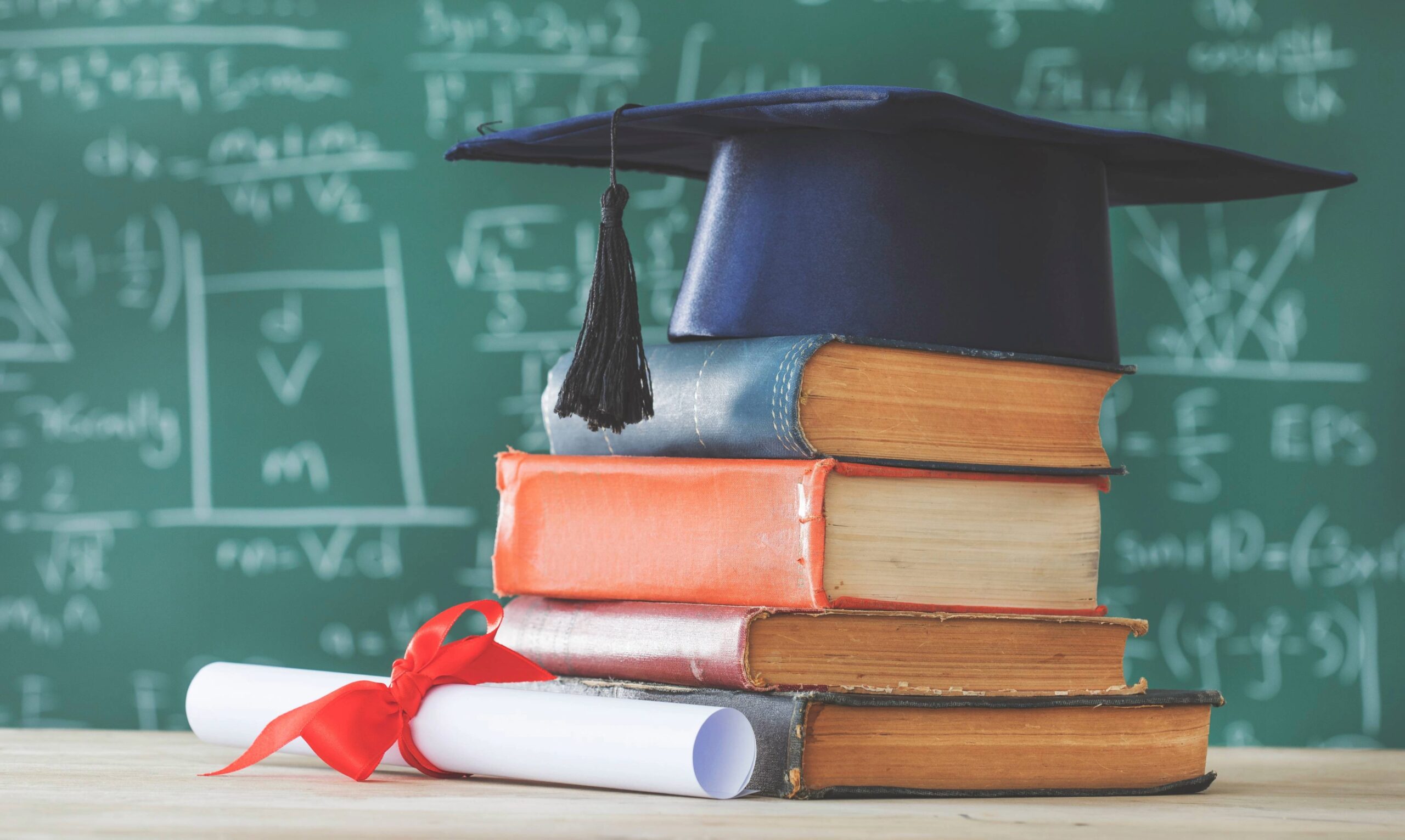 Graduation cap on stacked books with diploma representing student scholarship opportunity