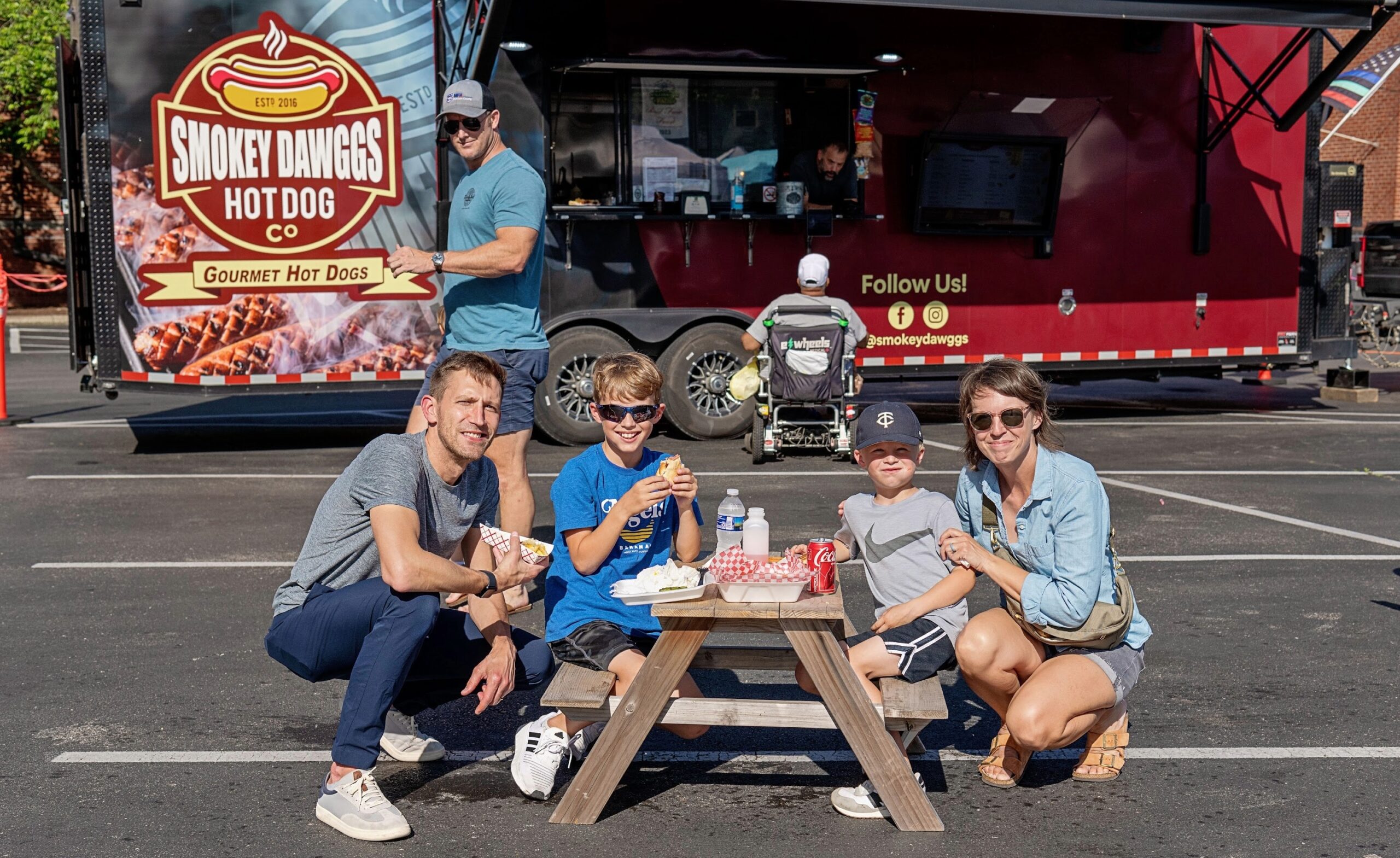 Family eating hot dogs at Smokey Dawggs food truck in Franklin Tennessee on a sunny day