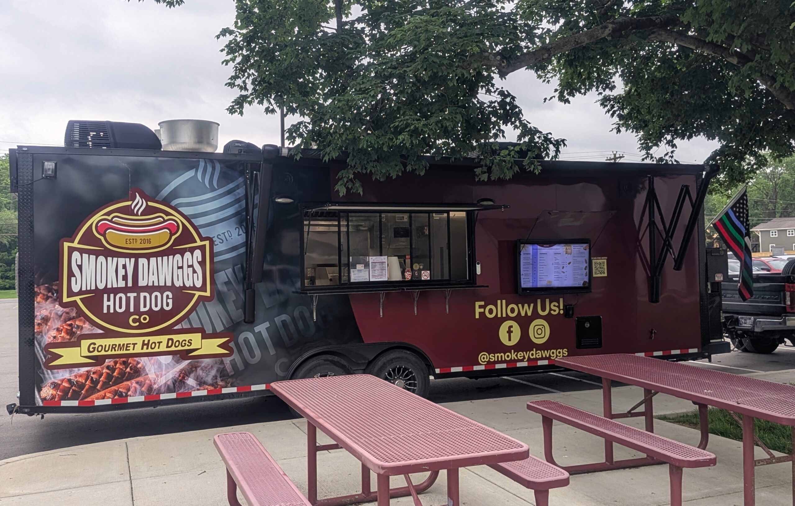 Smokey Dawggs gourmet hot dog food truck parked with outdoor picnic tables in Franklin Tennessee