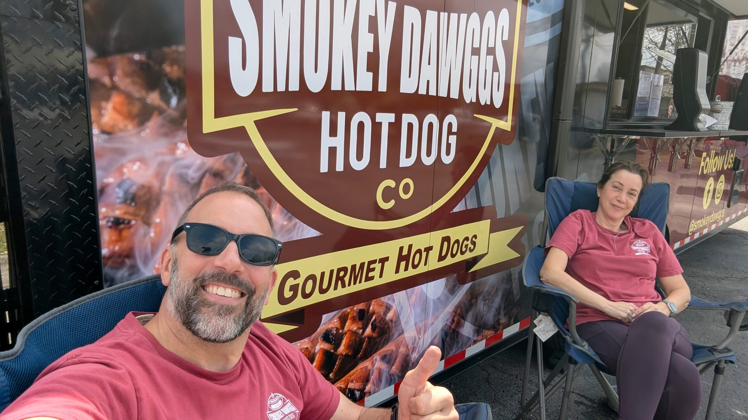 Jim and Stella Hendel of Smokey Dawggs sitting outside their gourmet hot dog food truck in Franklin Tennessee