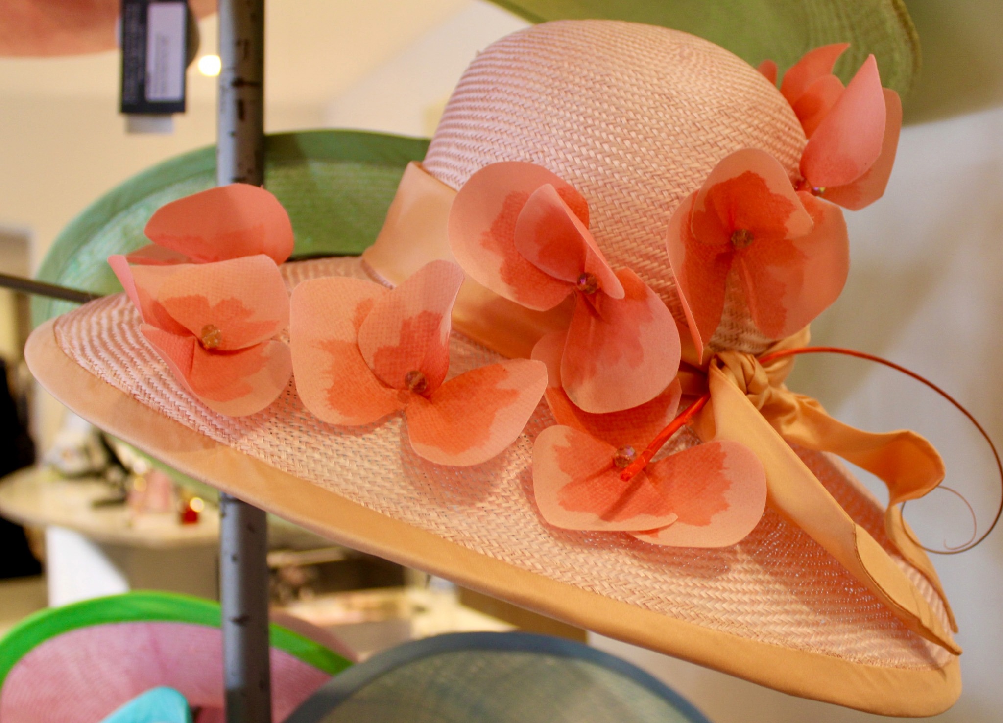 Peach wide-brim hat with floral accents by Christine Moore on display at Gus Mayer in Nashville for Iroquois Steeplechase fashion