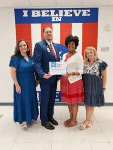 FIS PLC certificate.jpg: Kathy Natour of Solution Tree (left) presents the Freedom Intermediate administration (l-r) Joel Hoag, Tracie Gallon, and Amanda Potts, with the Model PLC at Work School certificate.