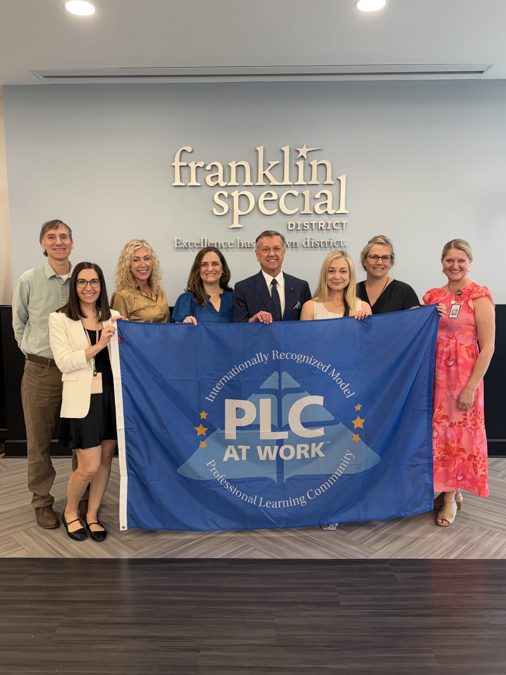 Franklin Special District's Guiding Coalition received the Model PLC at Work District flag from Solution Tree's Kathy Natour. Pictured are (left to right) Pax Wiemers, Shelly Robinson, Gina Looney, Kathy Natour, David Snowden, Mary Decker, Amber Whitley, and Summer Carlton.