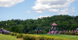 Horses race during the Iroquois Steeplechase in Nashville, Tennessee, with jockeys competing over jumps on the course.