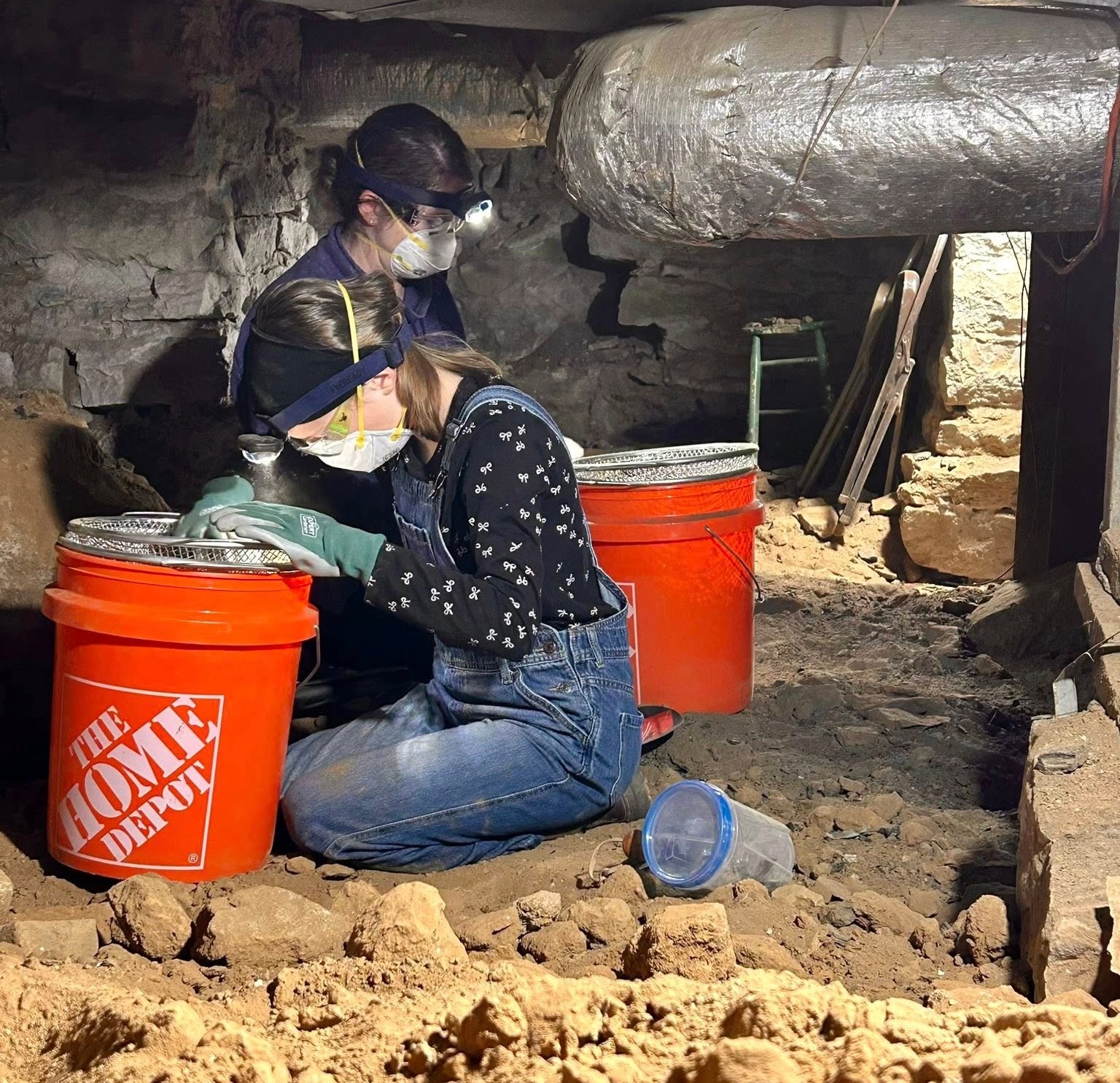 Lotz House Cellar Tour Franklin, TN guests wearing masks and gloves while searching for artifacts in the dirt-floored cellar.