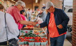 Two men selling and buying tomatoes at a Tennessee farmers market for the Tennessee Farmers Market Trail, photo by photographer Holly Rainey