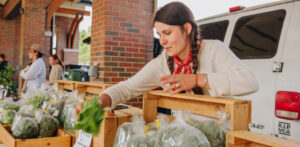 Woman setting up a fresh produce stand at a Tennessee farmers market for the Tennessee Farmers Market Trail. Photo by photographer Holly Rainey.