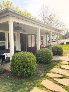 Crown Winery Leipers Fork in Franklin, TN, exterior front porch seating at and surrounded by greenery and creekside views.