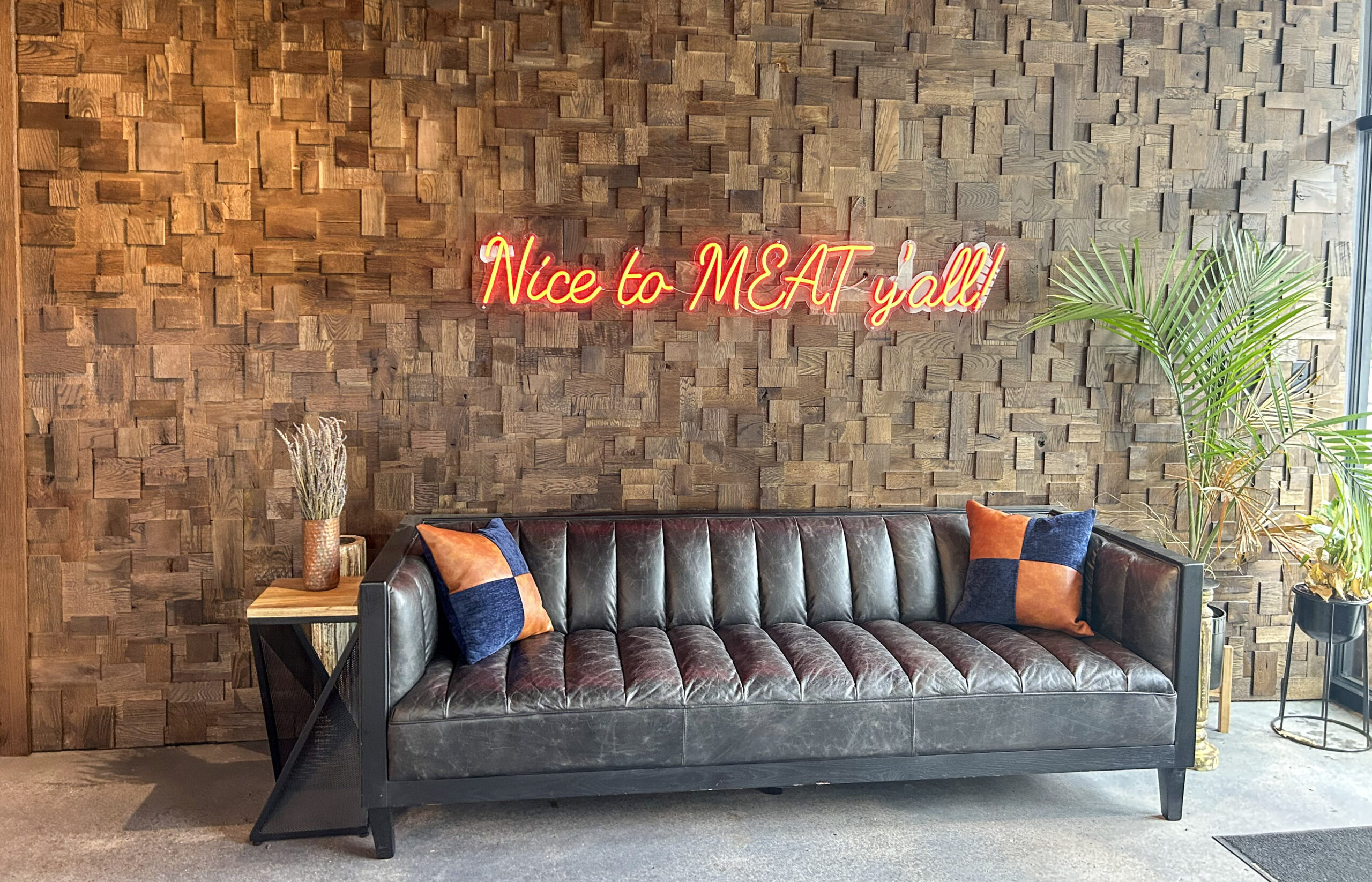 Nice to MEAT y’all neon sign above a leather sofa inside The Franklin Butchery in downtown Franklin TN