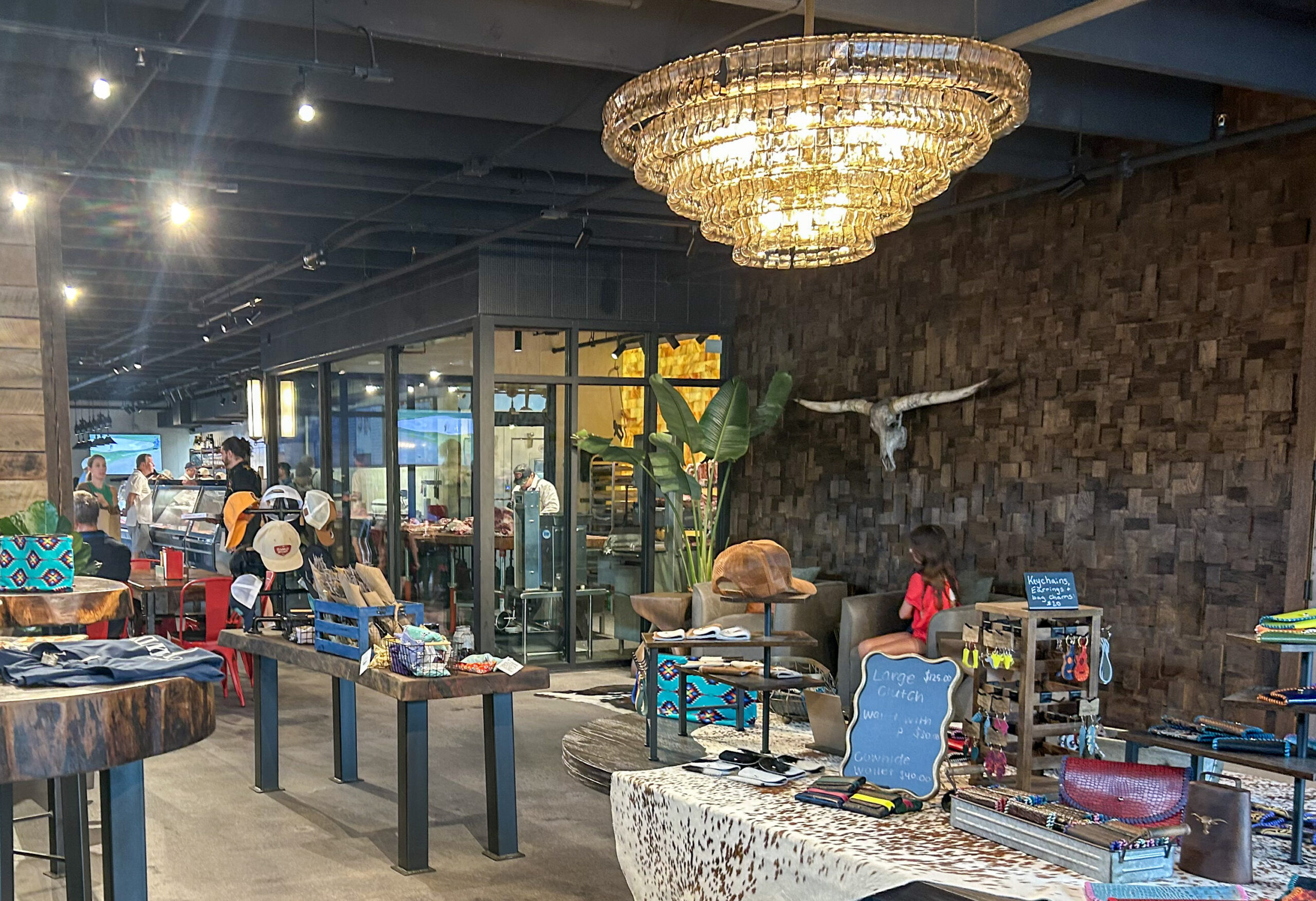 Retail area inside The Franklin Butchery in downtown Franklin TN with branded merchandise, leather goods, dining tables, and glass-walled cut room