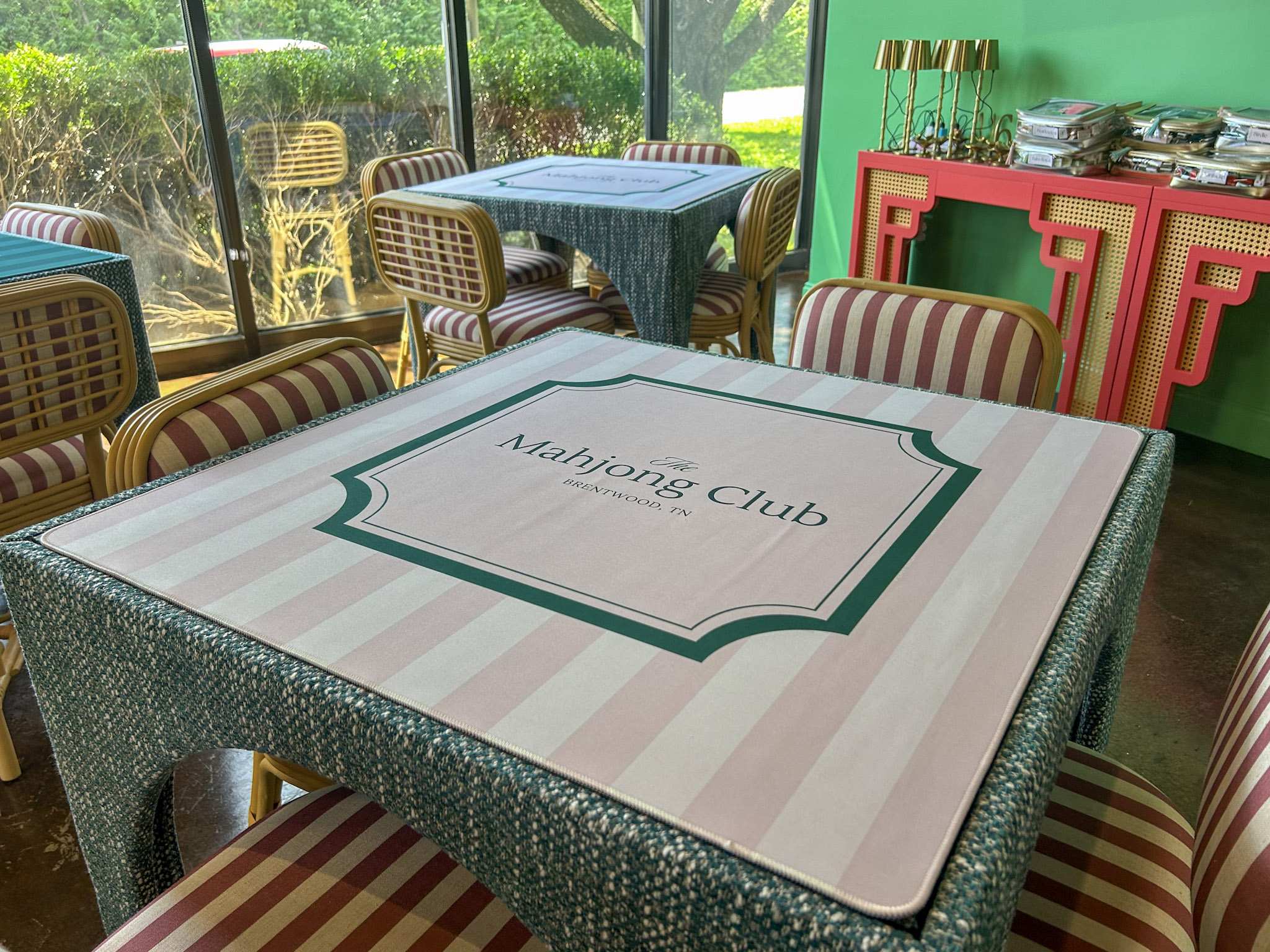 The Mahjong Club in Brentwood, TN, setup with branded mat and seating for Mahjong players. The Mahjong Club in Brentwood offers Monday-through-Saturday hours and online scheduling for lessons, games, open play, and special events.