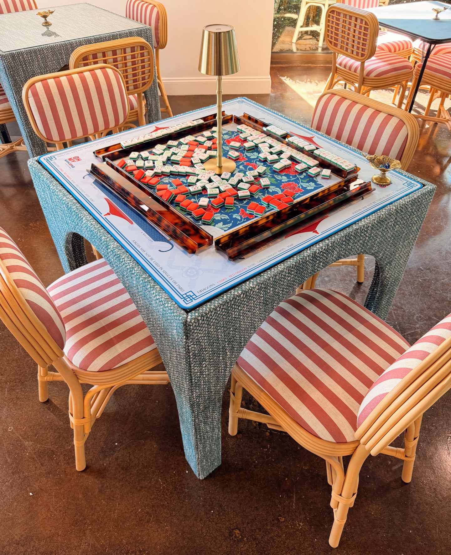 Mahjong table with tiles and striped chairs at The Mahjong Club in Brentwood, TN