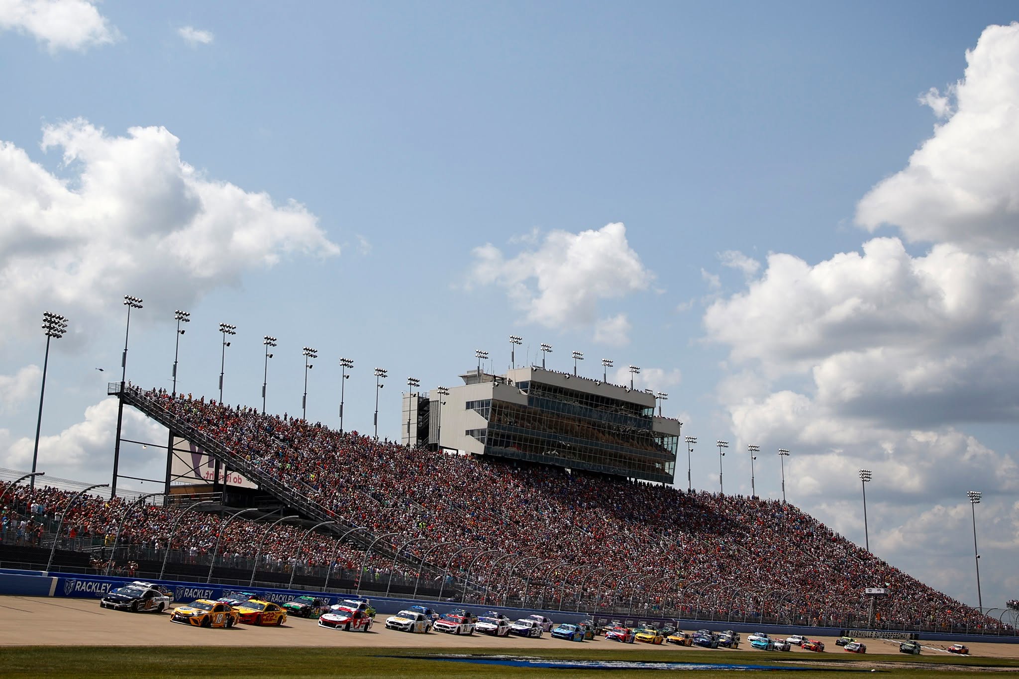 NASCAR race at Nashville Superspeedway in Lebanon, TN with cars on the track and fans in the grandstands