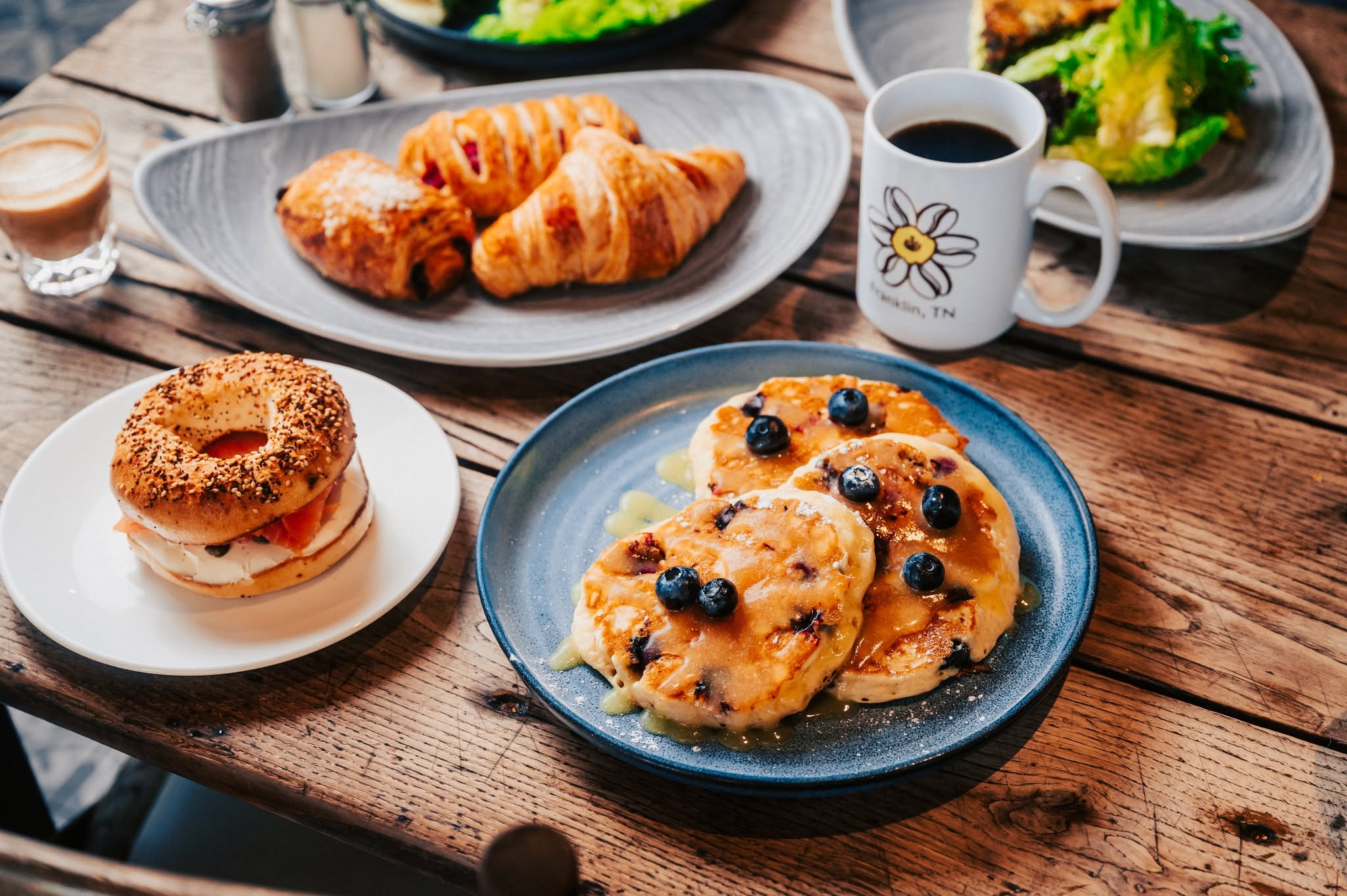 Brunch spread with pancakes, pastries, coffee, and a breakfast bagel at McGavock’s Coffee Bar in Franklin, TN.