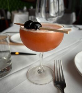 Cork and Cow in Franklin, TN serving Queen of Diamonds stone fruit cocktail with a garnish
