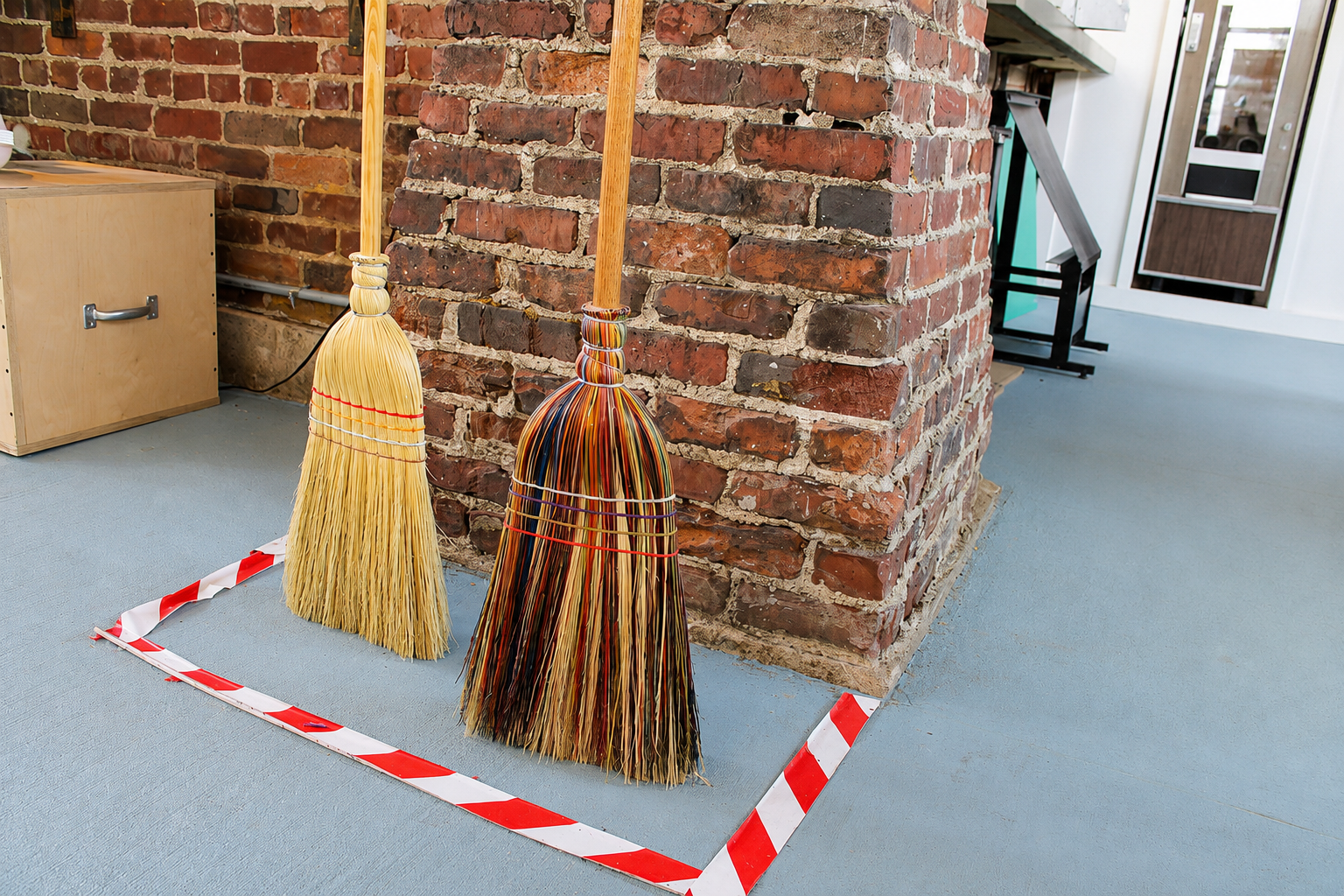 Two handmade brooms standing inside Experimart at The Factory at Franklin